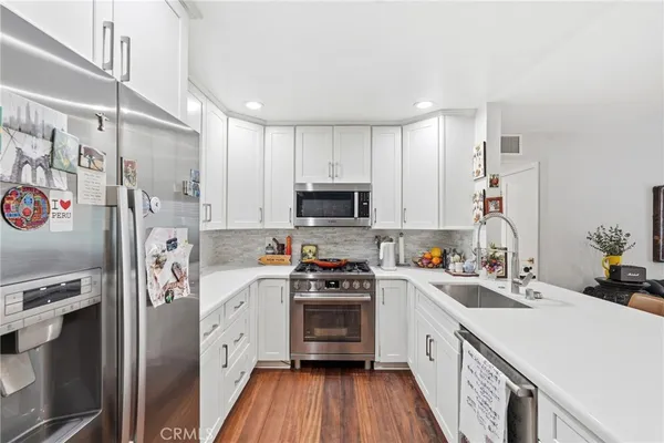 a kitchen with stainless steel appliances a refrigerator sink and white cabinets