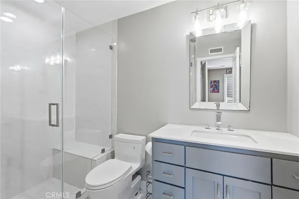a bathroom with a toilet a sink a mirror and shower