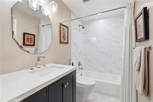 a bathroom with a sink a toilet a mirror a bathtub and shower