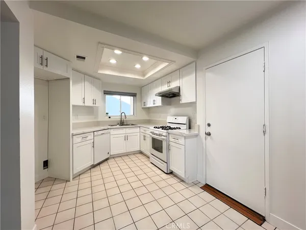 a kitchen with white cabinets a sink and white appliances