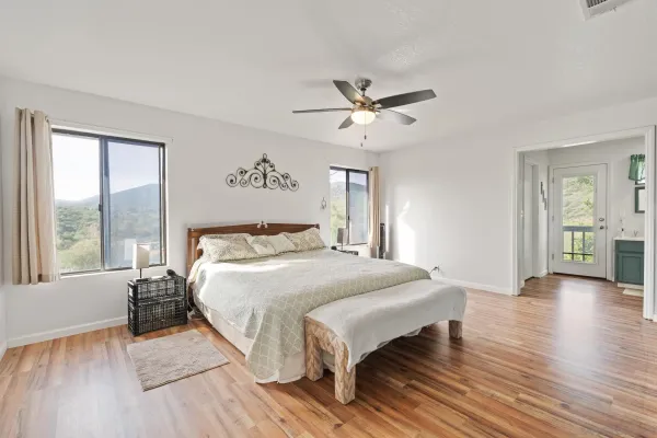 a spacious bedroom with a bed a window and wooden floor