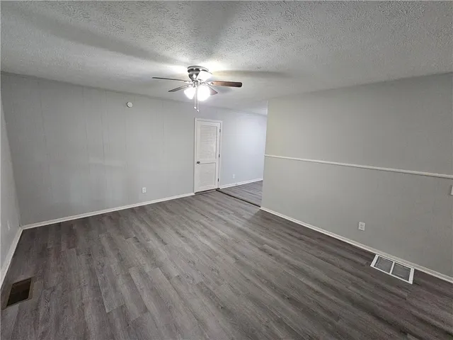 an empty room with wooden floor and ceiling fan