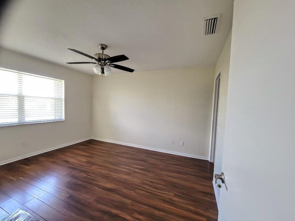 3105 Southeast Aster Lane, Unit 1806 Stuart, FL 34994 - Photo 18 of 45 an empty room with wooden floor fan and windows
