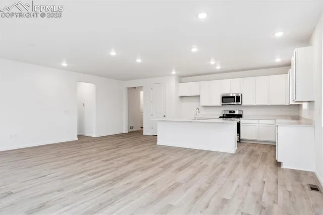 a view of kitchen with kitchen island stainless steel appliances refrigerator stove top oven and cabinets