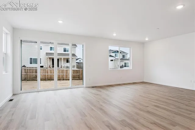 a view of empty room with wooden floor and window