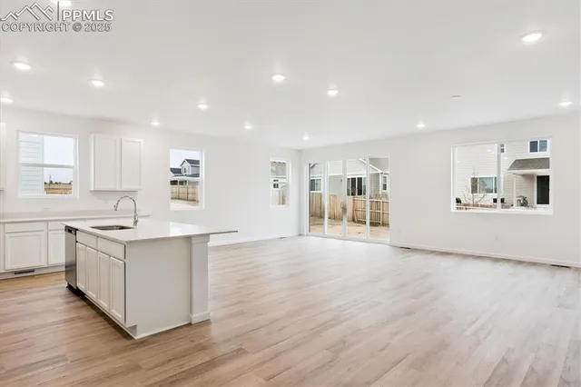 a large white kitchen with stainless steel appliances granite countertop a large center island and a wooden floors