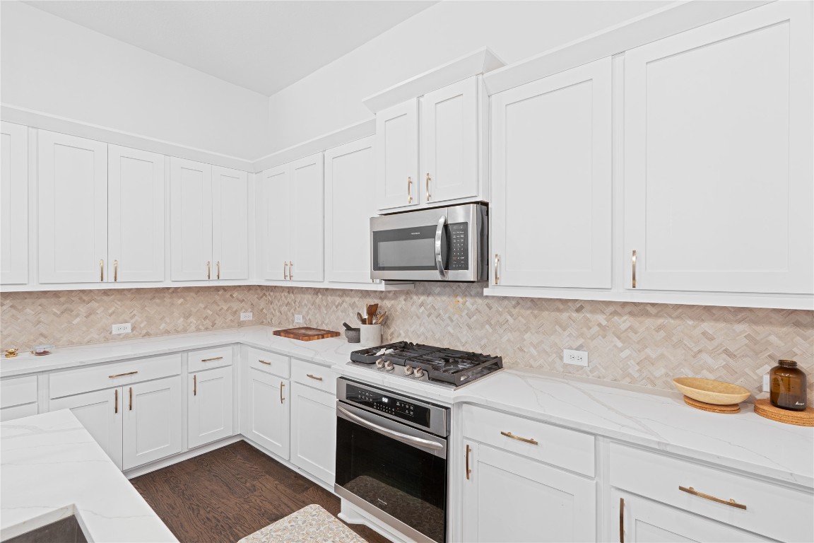 3037 Sage Ranch Drive Leander, TX 78641 - Photo 11 of 26 a kitchen with granite countertop white cabinets and white appliances