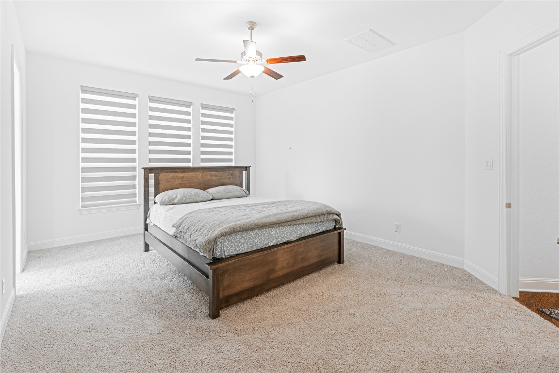 3037 Sage Ranch Drive Leander, TX 78641 - Photo 14 of 26 a bed sitting in a bedroom next to a window and a chandelier