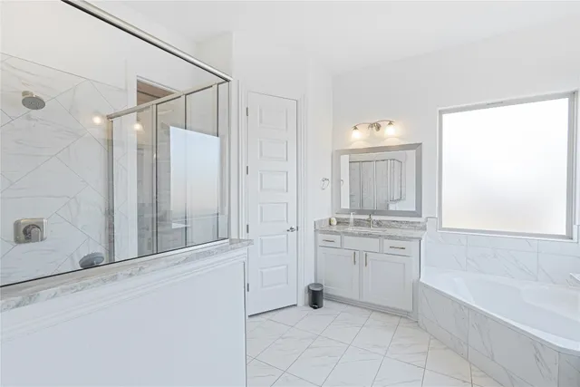 a bathroom with a granite countertop double vanity sink a mirror and a bathtub