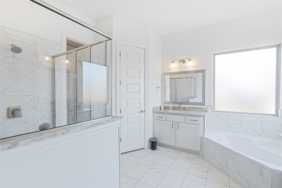 3037 Sage Ranch Drive Leander, TX 78641 - Photo 15 of 26 a bathroom with a granite countertop sink a mirror and a bathtub