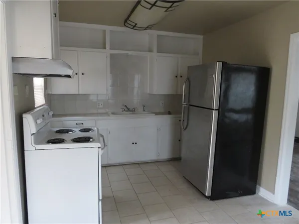 a kitchen with a refrigerator and a stove top oven