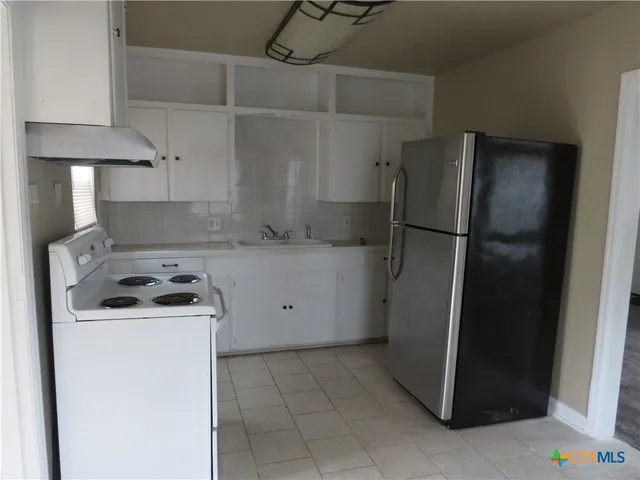 a kitchen with a refrigerator and a stove top oven