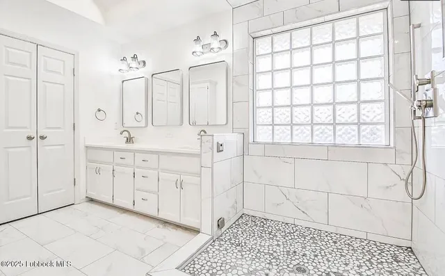a spacious bathroom with a granite countertop sink a mirror a and a shower