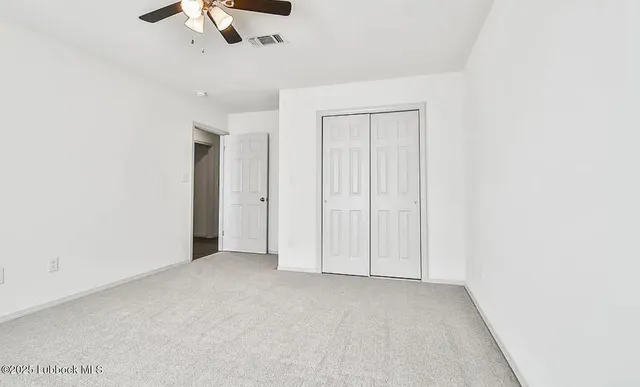 an empty room with chandelier fan