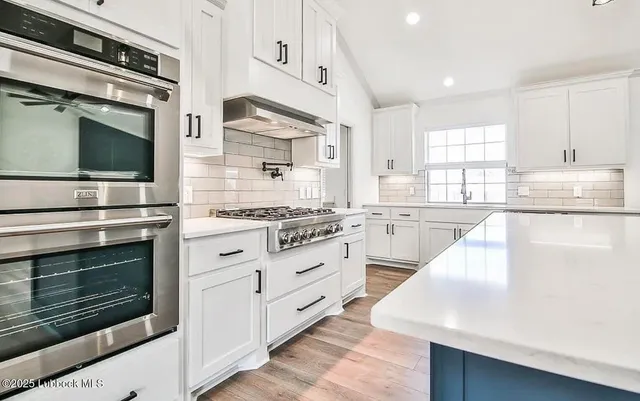 a kitchen with stainless steel appliances white cabinets and a stove top oven