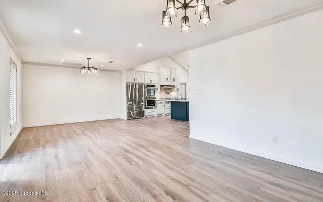 wooden floor in an empty room with a chandelier