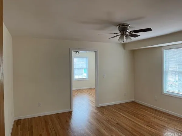 an empty room with wooden floor closet and windows