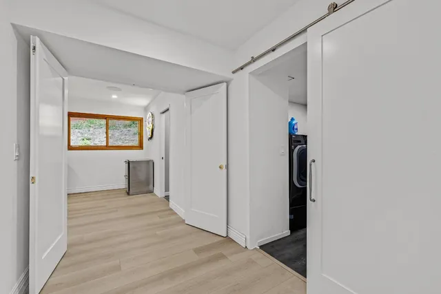 a view of a hallway with wooden floor and a bathroom