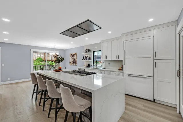 a kitchen with kitchen island a stove a table a sink and cabinets
