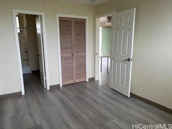 a view of a hallway with wooden floor and closet area