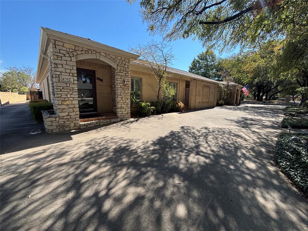 4702 Ranch View Road Fort Worth, TX 76109 - Photo 1 of 40 Stone-clad arched entryway with a solid door, brick exterior, and mature tree landscaping