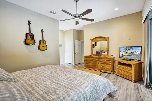 a bedroom with a bed and dresser with wooden floor