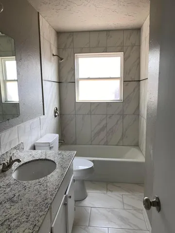 a bathroom with a granite countertop sink a toilet and shower