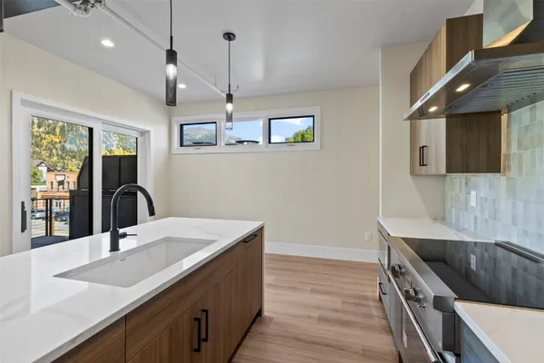 a kitchen with a sink and a stove with wooden floor