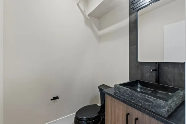 a bathroom with a granite countertop sink and a toilet