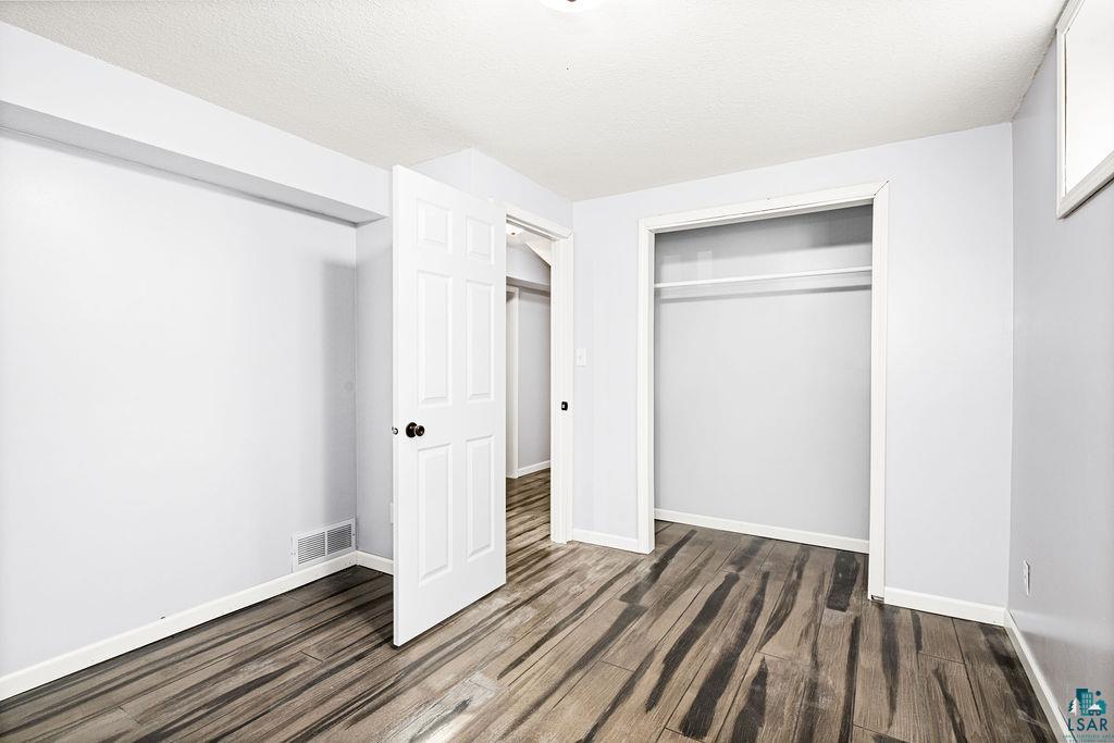 4002 Old Midway Road Hermantown, MN 55810 - Photo 12 of 19 Unfurnished bedroom with epoxy floor, a closet, and a textured ceiling