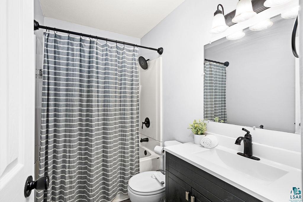 4002 Old Midway Road Hermantown, MN 55810 - Photo 9 of 19 Full bathroom featuring vanity, shower / bathtub combination with curtain, and toilet