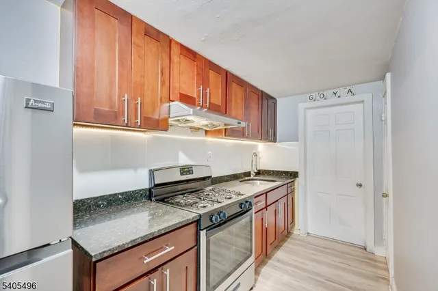 a kitchen with stainless steel appliances granite countertop a stove a sink and a refrigerator