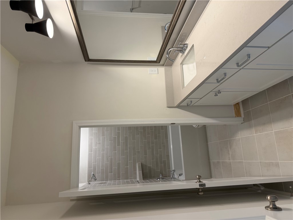 405 Botany Lane Anderson, SC 29621 - Photo 14 of 14 This sleek bathroom features a single vanity, a spacious mirror, and a tiled shower.