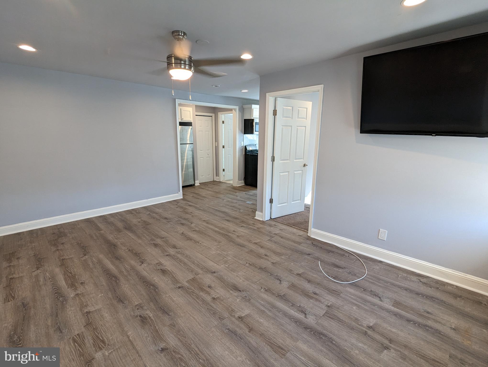 401 Montgomery Street, Unit 2 Laurel, MD 20707 - Photo 1 of 13 a view of an empty room with wooden floor and a flat screen tv