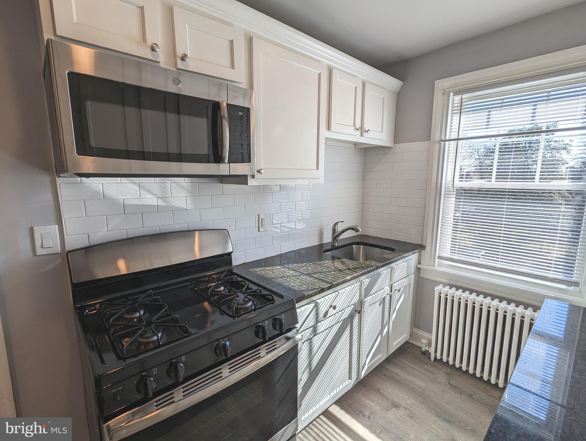 401 Montgomery Street, Unit 2 Laurel, MD 20707 - Photo 5 of 13 a kitchen with stainless steel appliances granite countertop white cabinets and a stove top oven