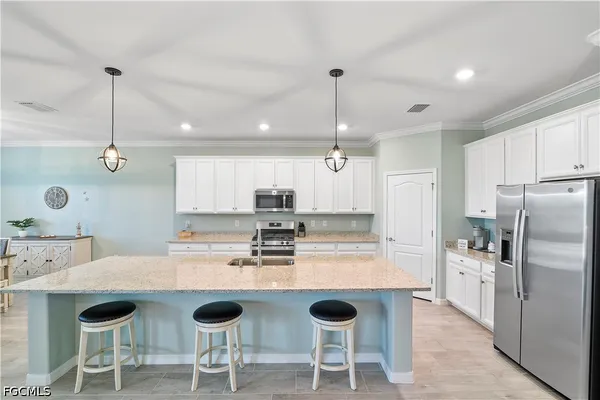 a kitchen with stainless steel appliances granite countertop a sink a stove a refrigerator cabinets and chairs