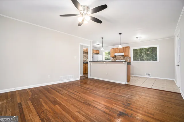 a view of a kitchen with wooden floor a ceiling fan and windows