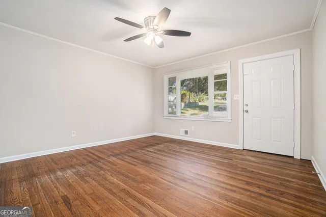 an empty room with wooden floor chandelier fan and windows