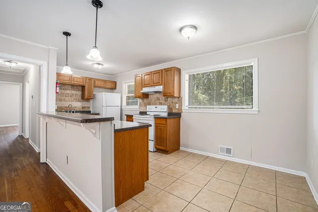 a kitchen with stainless steel appliances granite countertop a refrigerator a sink a stove and a wooden floors