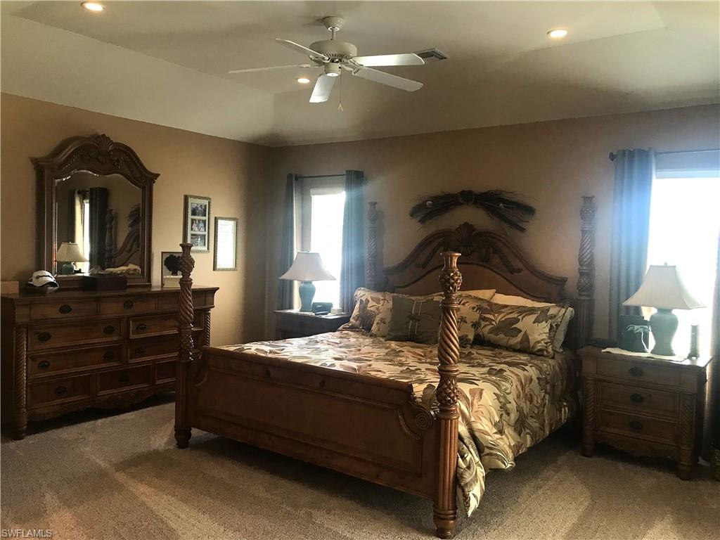 120 Forest Hills Boulevard Naples, FL 34113 - Photo 16 of 24 a bedroom with a bed and a chandelier