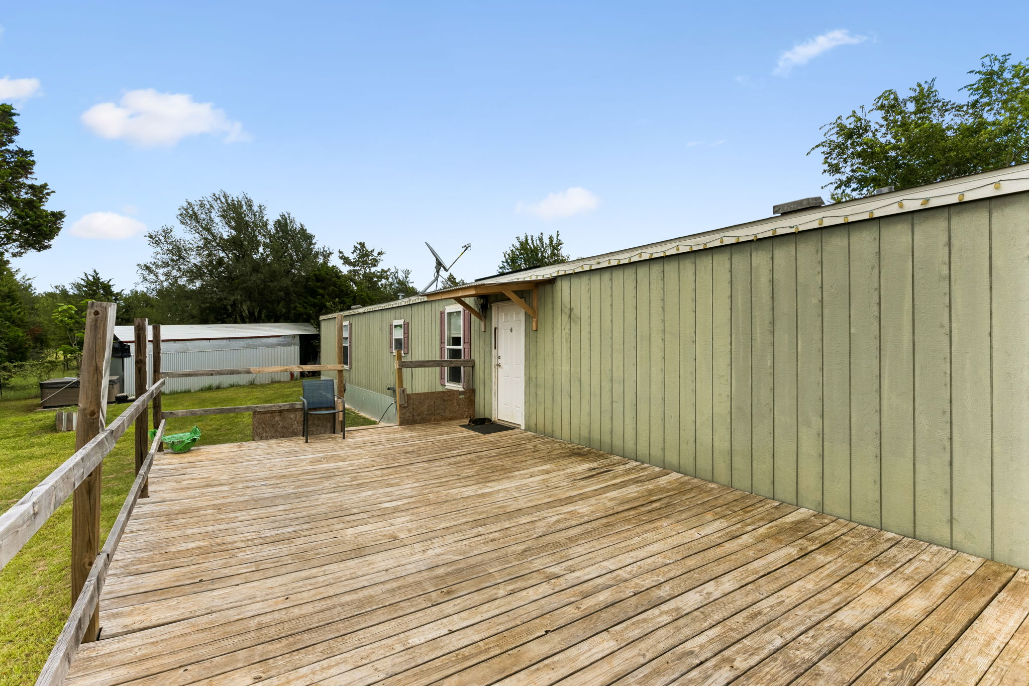 253 North County Line Road, Unit C Elgin, TX 78621 - Photo 3 of 39 A spacious wooden deck provides ample outdoor living space next to a verdant structure.