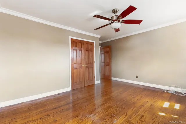 an empty room with wooden floor and ceiling fan