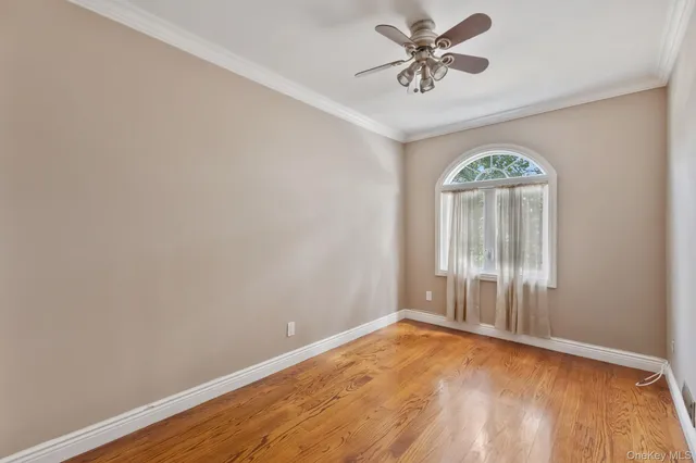 an empty room with a chandelier fan and windows