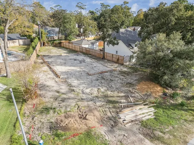 a view of a yard with plants and large trees