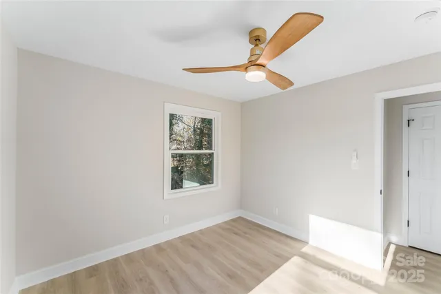 a view of a hallway with wooden floor and a chandelier fan
