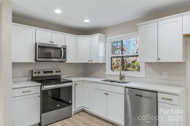 a kitchen with stainless steel appliances granite countertop a stove top oven a sink dishwasher and a refrigerator with wooden floor