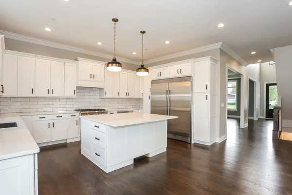 a view of a kitchen with kitchen island granite countertop wooden floor and stainless steel appliances