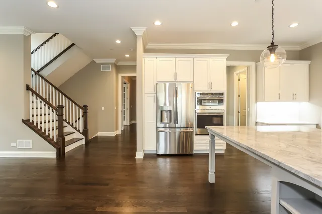 a view of an empty room and kitchen with window a ceiling fan and wooden floor