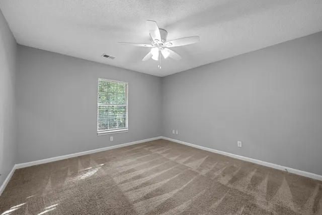 an empty room with a window and a fan