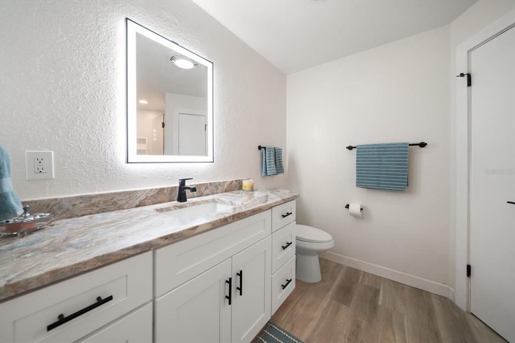 2505 Bay Boulevard, Unit 4 Indian Rocks Beach, FL 33785 - Photo 20 of 63 a bathroom with a granite countertop sink mirror vanity and toilet